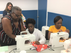 Volunteer Eunice Carroll (left) trouble-shoots a sewing machine issue.