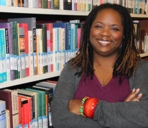 Dr. MELANYE PRICE's picture standing by the books in the library.