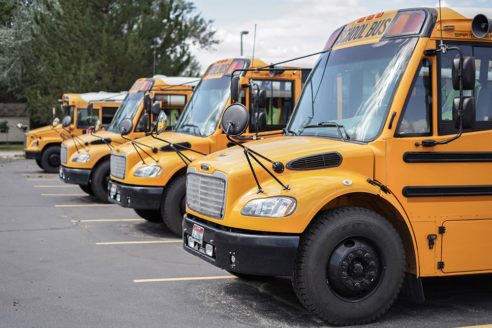 Four school buses lined up in a school parking lot
