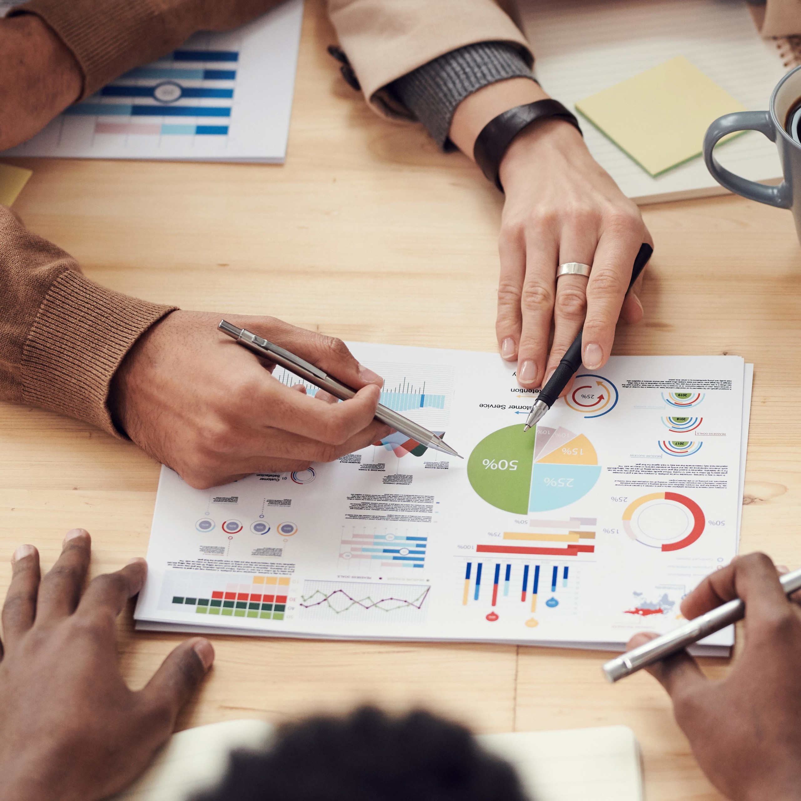 Men hands pointing at graphs on paper with pen