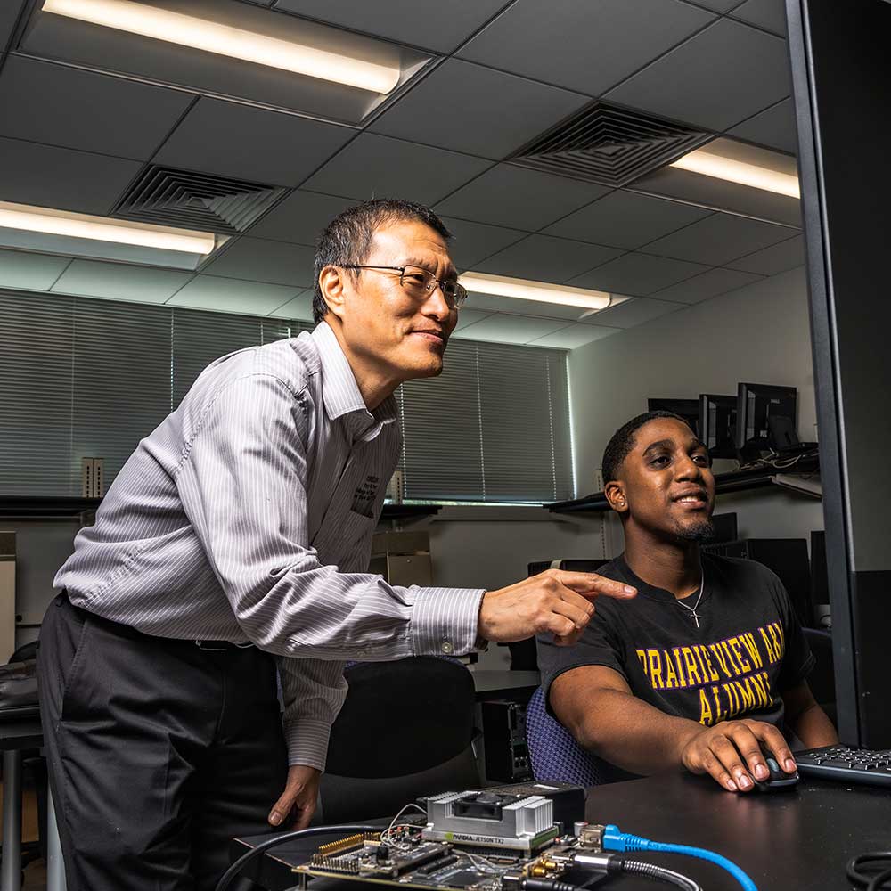 Faculty member working on a computer with a male student