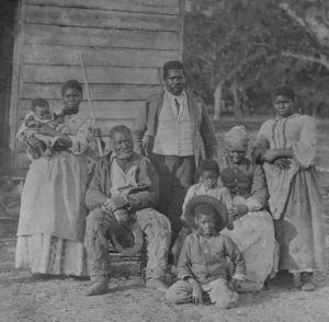 Slave family taking photo infront of their home