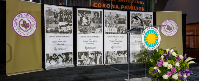 Stage with PVAMU Banners (PVAMU Seals, Pictures and Title - African American Studies at Prairie View A&M University), Podium with Smithsonian Seal, and Flowers
