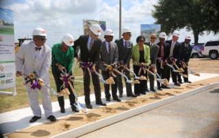 Members of the CAHS leadership team standing side by side holding shovels of dirt