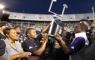 Eric Dooley hold State Fair Classic trophy surrounded by team