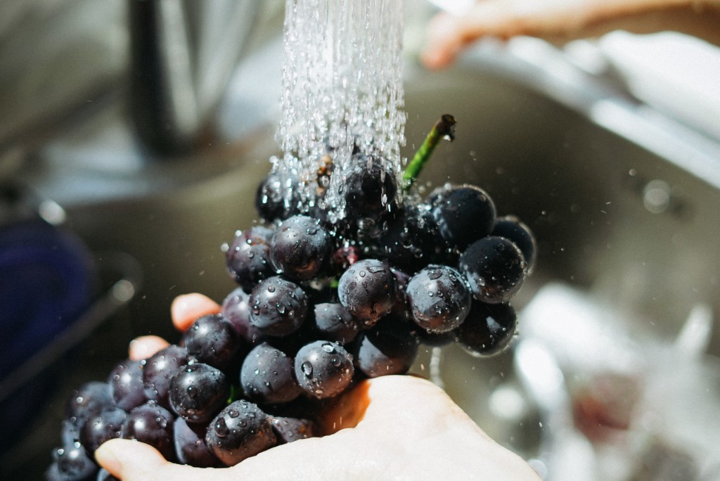 Person washing purple grapes|Photo by Manki Kim on Unsplash