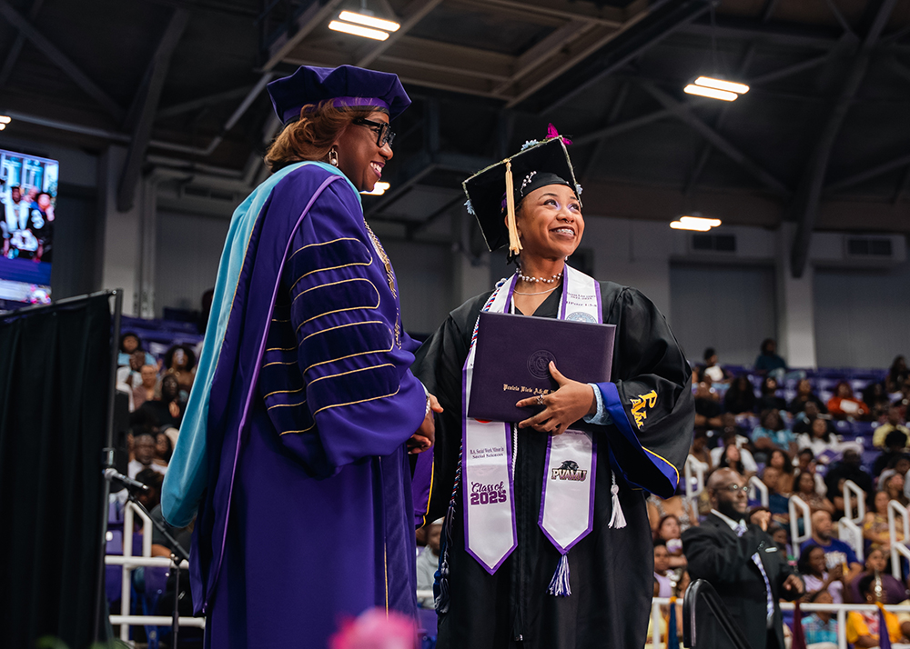 A 2025 graduate shakes hands with PVAMU’s ninth president, Dr. Tomikia P. LeGrande